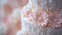 Delicate pink sugar flowers and white pearl decorations adorn wedding cake in soft focus, creating romantic pastel composition for celebration and bakery designs.