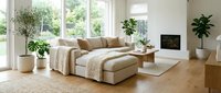 Spacious living room with beige modular sofa, wooden furniture, potted plants, and natural light from large windows, suitable for interior design and home decor projects.