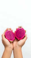 Hands holding two halves of vibrant magenta dragon fruit with black seeds against white background, showcasing fresh tropical produce for healthy eating and nutrition content.