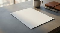 Blank white paper sheet on wooden desk with coffee mug and leather notebook in soft natural lighting for business presentations and mockup designs.
