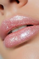 Close-up of glossy pink lips with sparkly glitter makeup effect showing white shimmer and shine, suitable for beauty and cosmetic advertising campaigns.