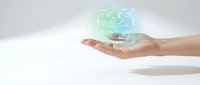 Close-up of a hand holding a glowing holographic cube displaying digital circuit patterns and technology symbols, representing innovation, data processing, and future tech solutions.