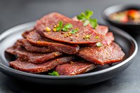 Sliced grilled beef steak with herbs on dark plate, cooked meat ready to serve for dinner or lunch meal preparation.