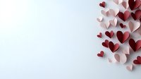 Red and pink paper hearts scattered on white background creating romantic corner composition, suitable for Valentine's day cards and love-themed designs.