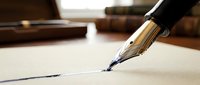 Elegant fountain pen with gold nib writing on cream paper in warm office setting with legal books in background for professional correspondence.