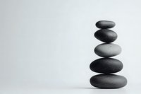 Balanced stack of smooth dark zen stones on white background, creating minimalist composition for wellness, meditation and spa concepts. Isolated photo.