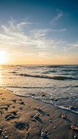 Serene ocean waves washing over sandy beach with scattered pebbles during golden hour sunset creating peaceful coastal atmosphere for relaxation and travel.