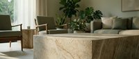 Elegant travertine stone coffee table in a bright modern living room with green plants and neutral furniture in soft natural light.