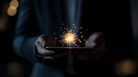 Glowing magical sparkler effect floating above smartphone in dark environment, held by person wearing dark clothing, creating mystical atmosphere.