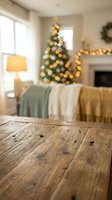 Rustic wooden table surface with blurred Christmas living room background featuring decorated tree, warm lights, cozy sofa and fireplace for holiday display.