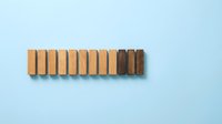 Wooden blocks arranged in a row on light blue background, showing progression from light to dark wood tones, representing growth, change, and business concepts.