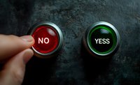 Finger pressing red NO button beside green YESS button on dark textured surface, representing choice and decision-making in business or life.