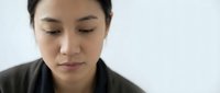 Young Asian woman with closed eyes in peaceful meditation pose against clean white background for wellness and mindfulness concepts.