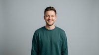 Young adult male with light skin tone, brown hair, and friendly expression wearing teal crewneck sweatshirt against neutral gray background for portrait and lifestyle use.