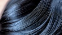 Silky smooth black hair waves creating elegant flowing curves and lines against dark background, showcasing healthy shine and movement for beauty and haircare marketing.