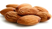 Fresh whole almonds with textured shells in natural brown color on white background, macro food photography showing detailed nutty texture and pattern.