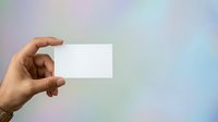 Hand holding blank white business card against soft blurred gradient background, ready for branding and corporate identity design projects.