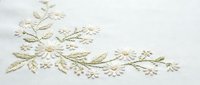 Delicate cream floral embroidery on white fabric featuring intricate botanical motifs and decorative stitching for textile and craft projects.