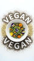 Vegan word made of chia seeds surrounding a white bowl with fresh microgreens and edible flowers on white background.