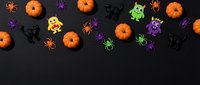 Halloween decorations with orange pumpkins, colorful spiders, bats and monsters on black background for seasonal party design and festive celebrations.
