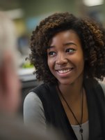 Young African American woman with curly hair smiling during conversation in office environment, showcasing positive workplace interaction.
