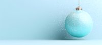Mint green Christmas ball ornament on light blue background with gentle sparkle effect and copy space for seasonal holiday designs and greetings.