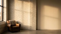 Modern minimalist interior with vintage leather armchair against white brick wall, natural sunlight streaming through window creating geometric shadows on floor.