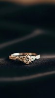 Elegant diamond engagement ring with intricate gold band featuring vintage-inspired details on dark textured surface for luxury jewelry marketing.
