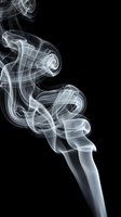White smoke swirling gracefully against a black background, forming elegant curves and abstract shapes in a dramatic studio shot.