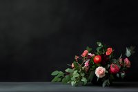 Dramatic floral arrangement with pink and red roses against dark background, creating moody atmosphere for wedding, anniversary, or luxury event styling.