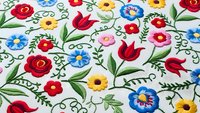 Colorful folk art embroidery pattern with roses, tulips and flowers on white fabric. Traditional floral design for textile, craft and decorative projects.