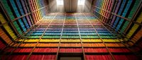 Colorful rainbow gradient library bookshelf corridor with symmetrical perspective leading to bright light, creating vibrant literary tunnel effect.