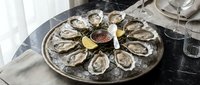 Fresh oysters on ice served on a rustic metal platter with lemon wedges and mignonette sauce, elegant seafood dining.