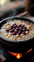 Hot steaming bowl of mixed bean soup with red kidney beans and chickpeas cooking over open flame on rustic wooden table for comfort food recipes.