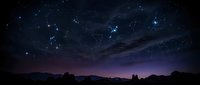 Starry night sky with constellation patterns over mountain silhouettes and desert landscape creating magical astronomy scene for educational materials.
