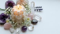 Healing crystals gemstones with lit candle and dried flowers for meditation spiritual wellness energy cleansing ritual aromatherapy relaxation.