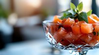 Fresh diced salmon with herbs and greens served in crystal bowl on blurred background, elegant restaurant appetizer presentation for menu and food service.
