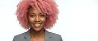 Professional African American businesswoman with vibrant pink curly hair smiling confidently in gray suit jacket on white background for corporate branding.