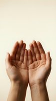 Open cupped hands reaching upward in prayer or receiving gesture against neutral beige background for spiritual and wellness concepts.