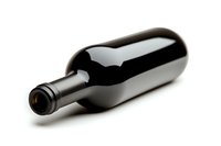 Empty dark glass wine bottle lying on white background, minimalist composition with soft shadows, isolated object for product photography and design.