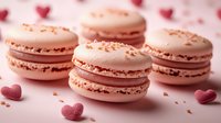 Pink macarons with delicate filling garnished with crumbs on light background with heart decorations, romantic dessert composition for Valentine's Day celebration.