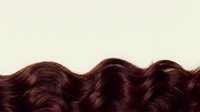 Shiny dark brown wavy hair strands isolated on neutral background, suitable for haircare, beauty, and cosmetic product marketing and design projects.