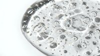 Close-up of water droplets and bubbles on a metallic surface, creating an abstract pattern of liquid spheres and reflections for design and background use.