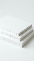 Three white handbound notebooks stacked on a light surface, showcasing exposed Coptic stitch binding and textured paper edges.