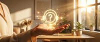 Young professional holding glowing question mark symbol in modern office workspace with natural sunlight, representing inquiry, support, help, and customer service solutions.