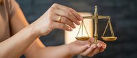 Female hands holding golden scales of justice symbol representing legal balance, law, attorney services, and judicial system concepts.