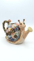 Ceramic snail-shaped watering can with whimsical character design, featuring floral patterned shell, wooden texture body, and perforated spout for gardening and plant watering.