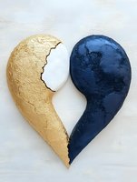 Broken heart sculpture in gold and navy blue on white background, featuring textured metallic surfaces and clean split design. Modern artistic representation.