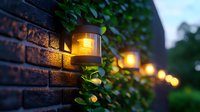 Glowing outdoor solar lights mounted on brick wall with green foliage create warm ambiance at dusk, illuminating garden path with soft golden bokeh effect.