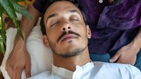 Young Hispanic man relaxing with closed eyes during professional massage therapy session at luxury spa wellness center for stress relief and rejuvenation.